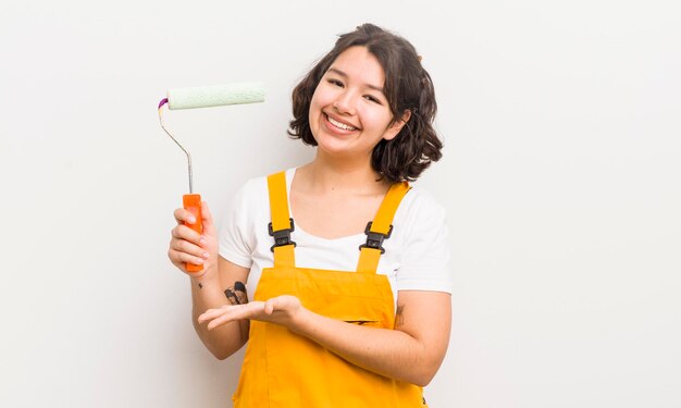 Menina bonita hispânica sorrindo alegremente se sentindo feliz e mostrando um conceito de pintura em casa