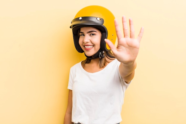 Menina bonita hispânica sorrindo e parecendo amigável mostrando o conceito de moto número cinco