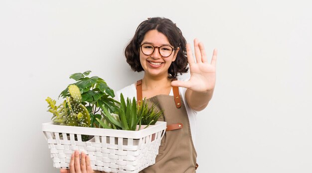 Menina bonita hispânica sorrindo e parecendo amigável mostrando o conceito de plantas número cinco