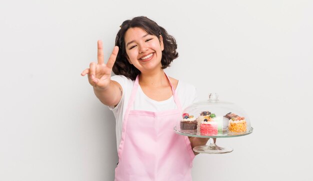 Menina bonita hispânica sorrindo e parecendo feliz gesticulando vitória ou paz feita em casa conceito de bolos