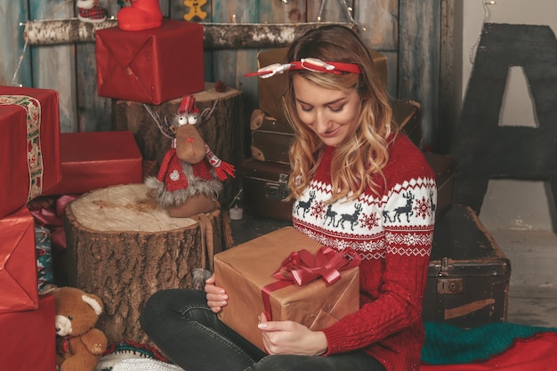 Menina bonita jovem em uma imagem de ano novo entre os presentes e decorações do feriado