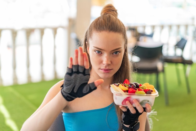 Menina bonita jovem esporte segurando uma tigela de frutas ao ar livre