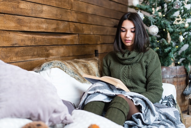 Foto menina bonita lendo um livro em uma atmosfera de natal