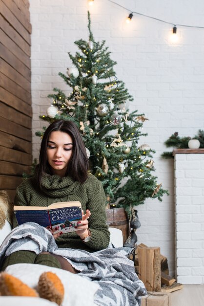 Menina bonita lendo um livro em uma atmosfera de Natal