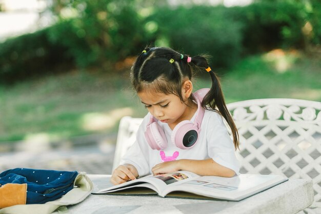 Menina bonita lendo um livro no jardim conceito de educação