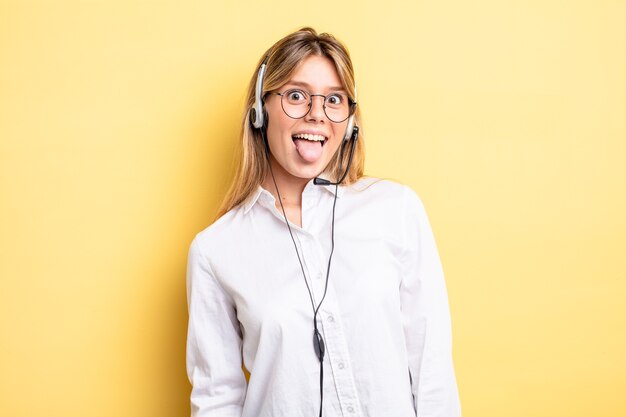 Menina bonita loira com atitude alegre e rebelde, brincando e mostrando a língua. conceito de fone de ouvido