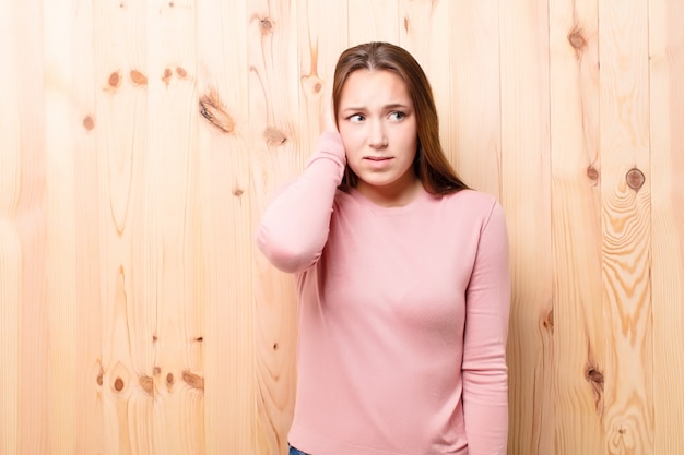 Menina bonita loira jovem contra a parede de madeira