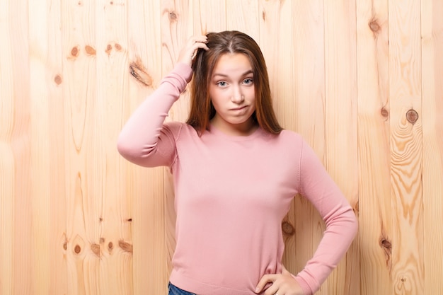 Foto menina bonita loira jovem contra a parede de madeira