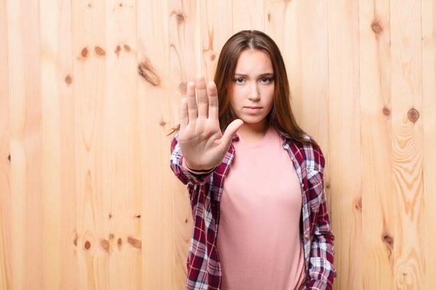 Menina bonita loira jovem contra a parede de madeira