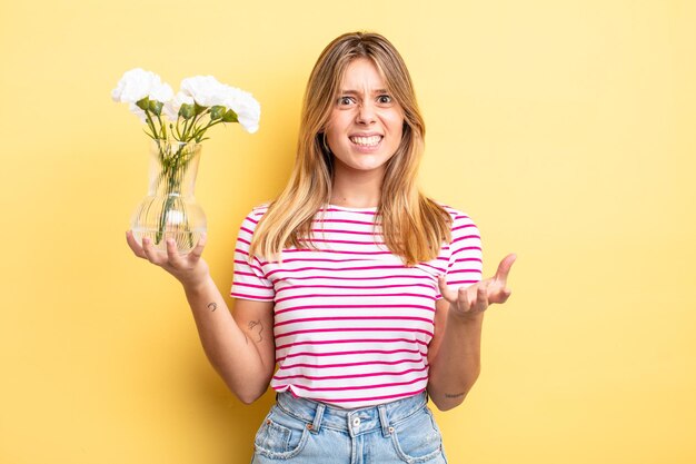 Menina bonita loira olhando com raiva irritada e frustrada conceito de flores decorativas