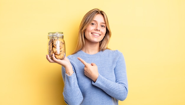 Menina bonita loira parecendo animada e surpresa, apontando para o lado. conceito de biscoitos caseiros