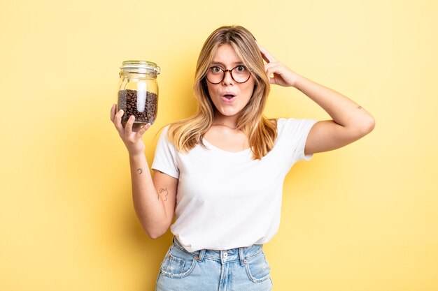 Menina bonita loira parecendo feliz, espantada e surpresa. conceito de grãos de café