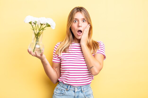 Menina bonita loira se sentindo chocada e assustada. conceito de flores decorativas