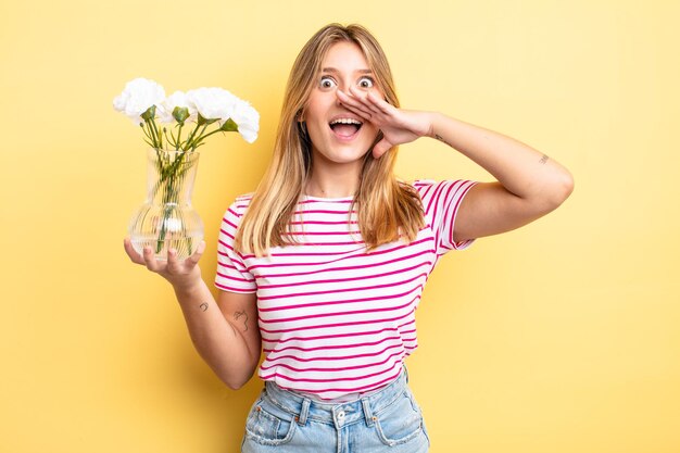 Menina bonita loira se sentindo feliz, dando um grande grito com as mãos ao lado da boca. conceito de flores decorativas