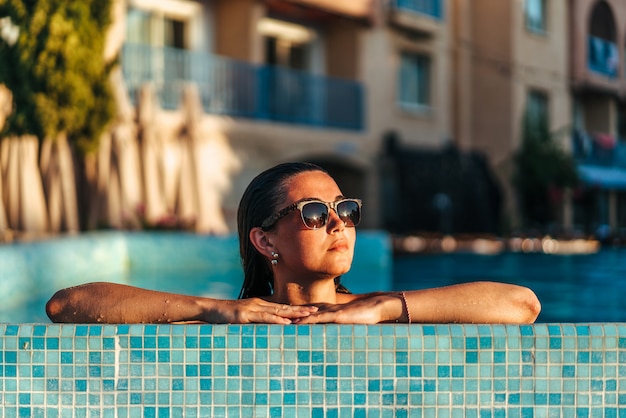 Menina bonita morena relaxante na piscina