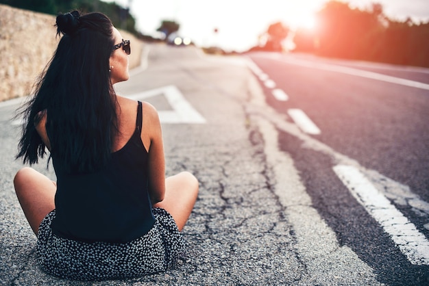 Menina bonita morena turista sentado na estrada