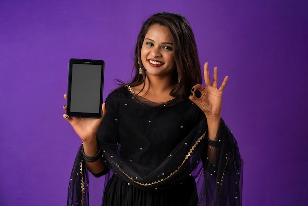 Menina bonita mostrando uma tela em branco de smartphone ou celular ou tablet