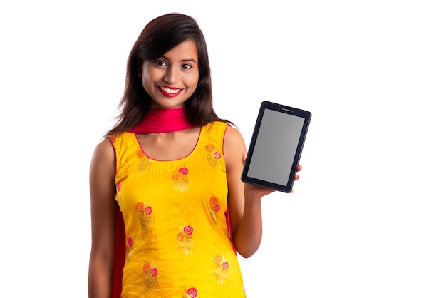 Menina bonita mostrando uma tela em branco de um smartphone ou celular ou tablet em um fundo branco