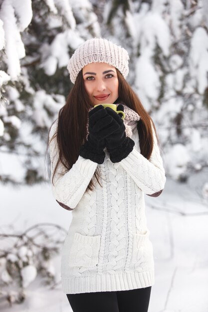 Menina bonita na floresta no inverno com uma xícara de chá.