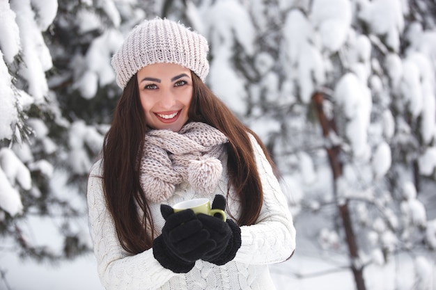 Menina bonita na floresta no inverno com uma xícara de chá.