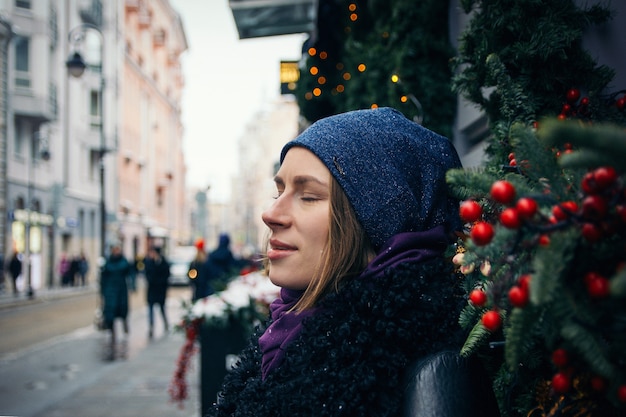 Menina bonita na rua no inverno no fundo das decorações de Natal