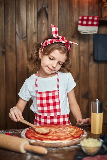 Menina bonita no avental xadrez, cozinhar pizza