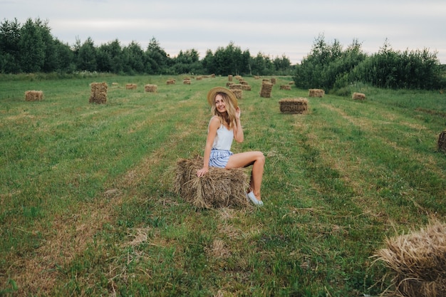 menina bonita no campo. mulher e fardos de feno. loira com um chapéu de palha. vida na vila