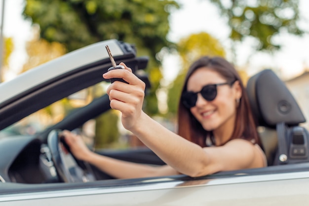 Menina bonita no carro cabrio conversível em um dia ensolarado em uma cidade