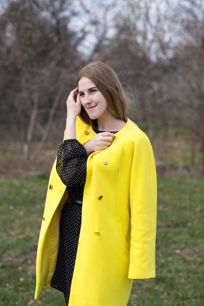 Menina bonita no casaco amarelo lá fora