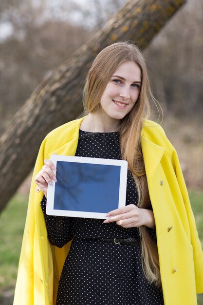 Menina bonita no casaco com tablet