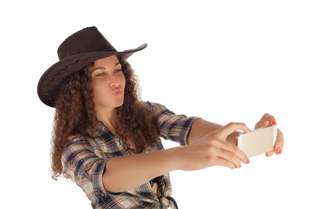 Menina bonita no estilo cowboy, fazendo selfie em seu smartphone.