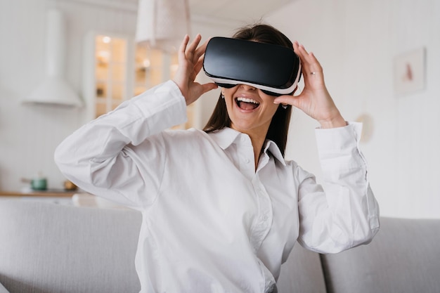 Menina bonita no fone de ouvido de realidade virtual Mulher feliz de realidade aumentada segura óculos 3D vr dentro de casa