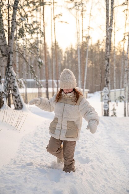 Foto menina bonita no inverno caminha na floresta coberta de neve no inverno atividades de inverno passeio de caminhada