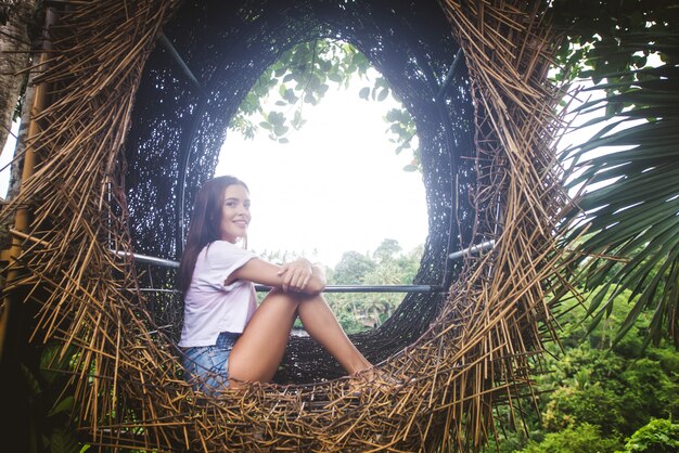 Foto menina bonita no ninho decorativo na selva da ilha de bali, indonésia