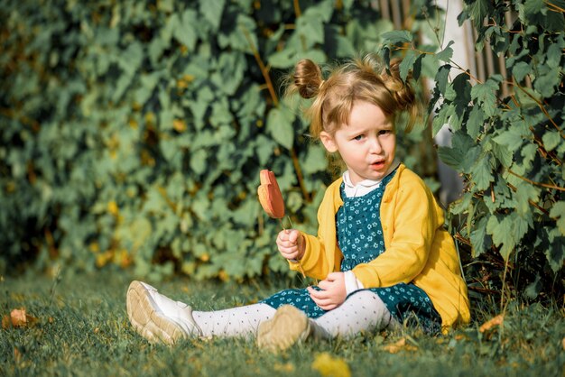 Menina bonita no parque outono comendo pirulito.