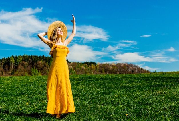 Menina bonita no vestido amarelo e no prado da montanha com dentes-de-leão.