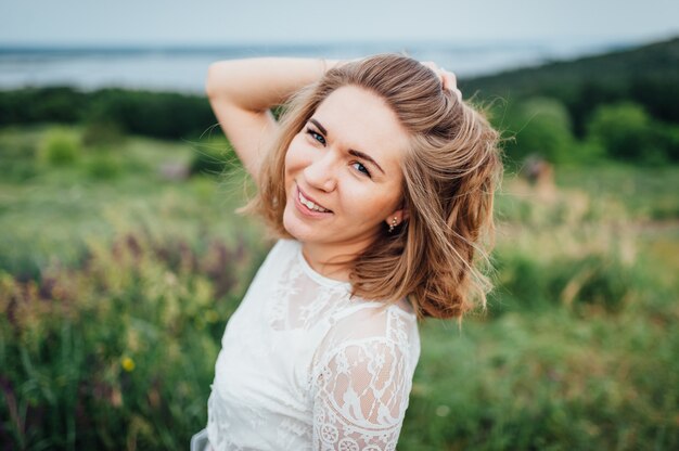 Menina bonita no vestido branco encontra-se na grama verde