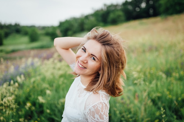 Menina bonita no vestido branco encontra-se na grama verde