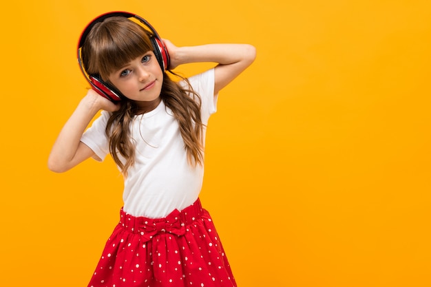 Menina bonita no vestido ouve música isolada em amarelo ou laranja