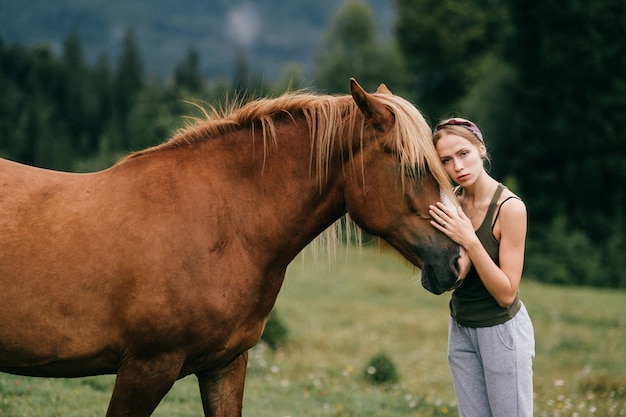 Menina bonita nova que abraça o cavalo na natureza.