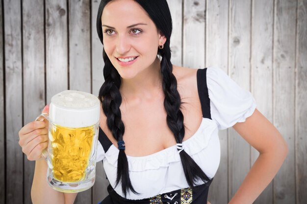 Foto menina bonita oktoberfest segurando caneca de cerveja contra pranchas de madeira