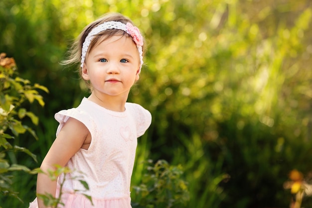 Menina bonita olhando para longe enquanto está de pé contra as plantas