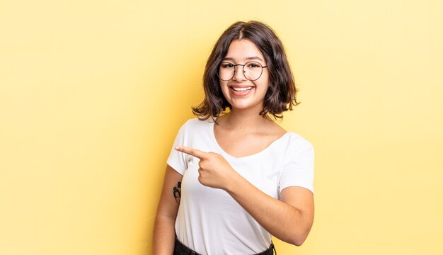 Menina bonita parecendo animada e surpresa, apontando para o lado e para cima para copiar o espaço