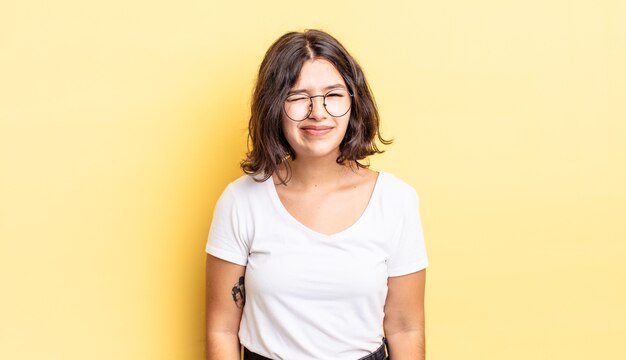 Menina bonita parecendo feliz e amigável, sorrindo e piscando os olhos para você com uma atitude positiva