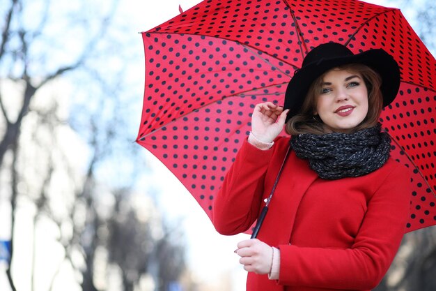 Menina bonita passeando com guarda-chuva vermelho na cidade