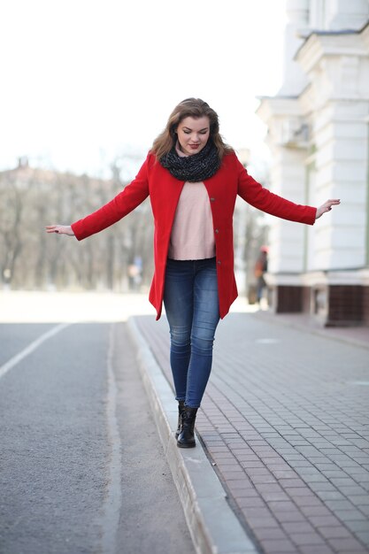 Menina bonita passeando com um casaco vermelho na cidade