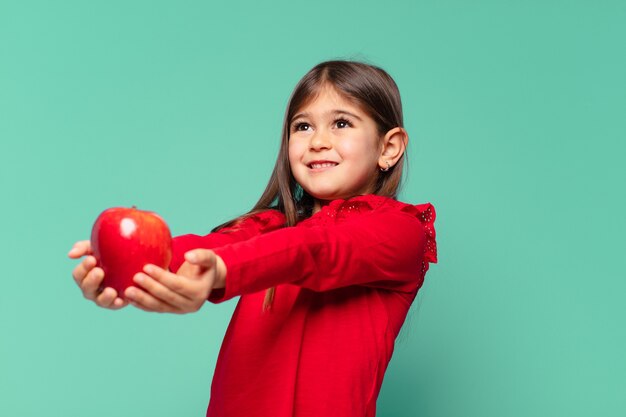 Menina bonita pensando em expressão e segurando uma maçã