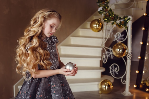 Menina bonita perto da árvore do ano novo. linda garota de vestido perto de árvore de natal, esperando o feriado. interior com decorações de natal.