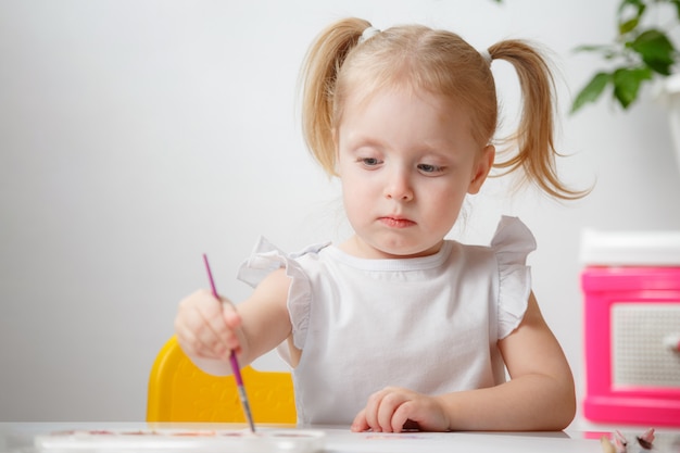 Menina bonita pintando com aquarela em casa