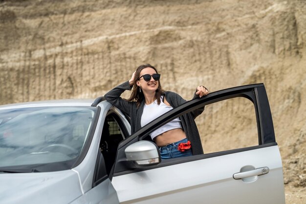 Menina bonita posando perto do carro em uma pedreira de areia